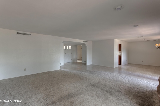 carpeted spare room featuring an inviting chandelier