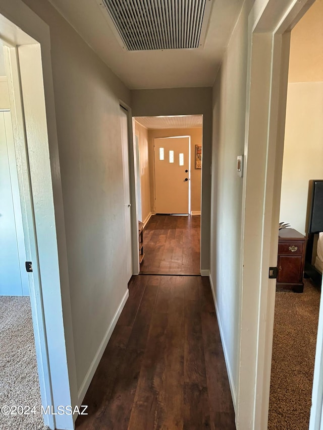 hall with baseboards, wood-type flooring, and visible vents