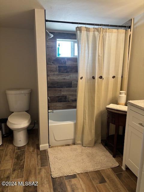 bathroom with vanity, wood finished floors, shower / bath combination with curtain, and toilet