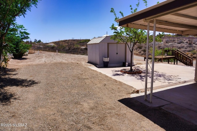view of yard with a patio, an outdoor structure, stairs, and a storage unit