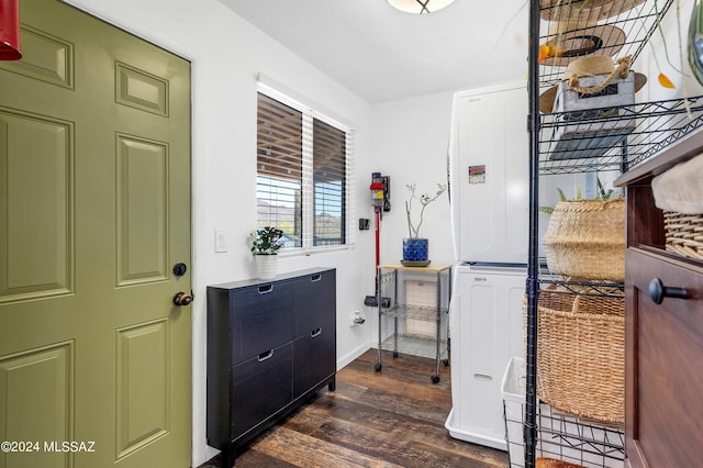 clothes washing area with stacked washing maching and dryer and dark hardwood / wood-style flooring