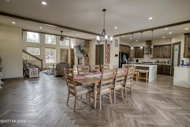 dining room with beamed ceiling, light parquet flooring, a brick fireplace, and ceiling fan