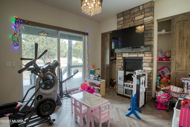 workout area with a fireplace, an inviting chandelier, and parquet flooring