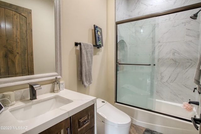 full bathroom with vanity, bath / shower combo with glass door, and toilet