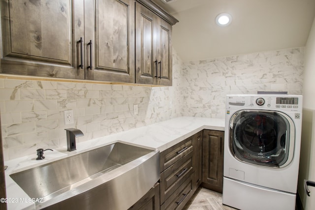 clothes washing area with cabinets, washer / dryer, light parquet flooring, and sink