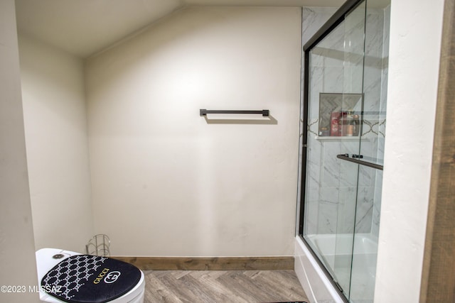 bathroom featuring toilet, wood-type flooring, bath / shower combo with glass door, and vaulted ceiling