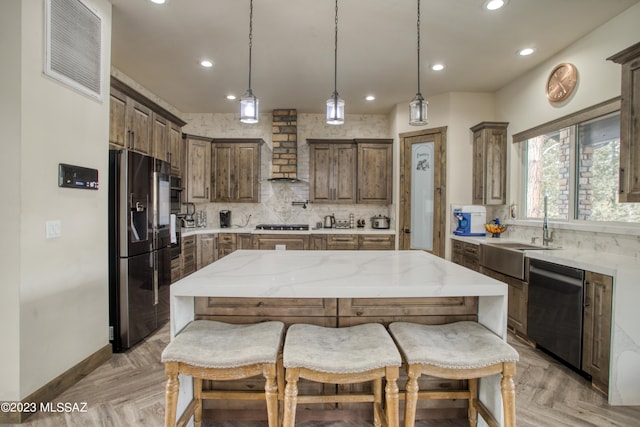 kitchen with a center island, light parquet floors, black fridge, wall chimney range hood, and stainless steel dishwasher