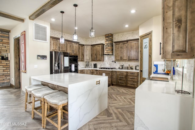 kitchen featuring custom exhaust hood, black double oven, stainless steel fridge, beamed ceiling, and a kitchen island