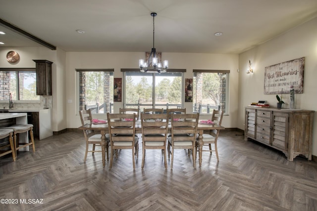 dining space featuring dark parquet flooring, sink, and a chandelier