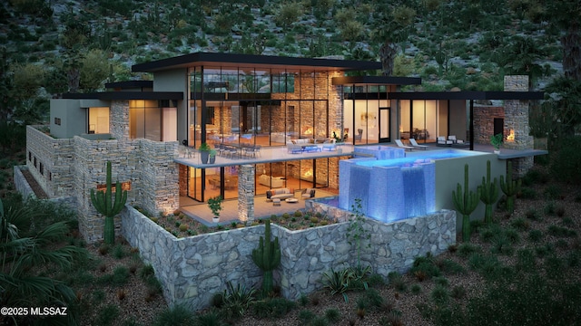 rear view of house featuring stone siding, stucco siding, a patio area, and an outdoor pool