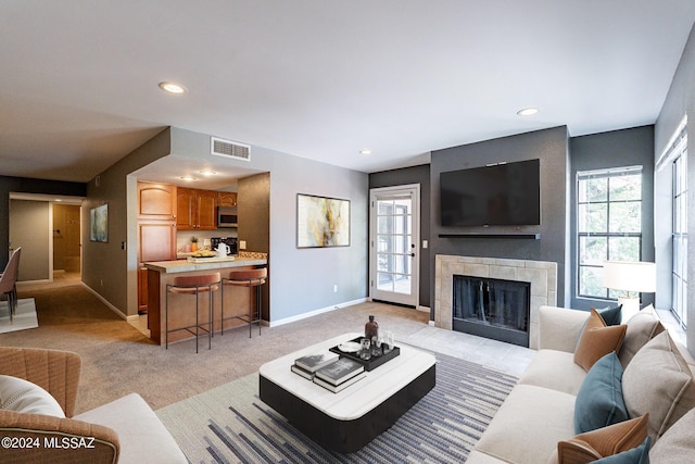 living room with light carpet and a tiled fireplace