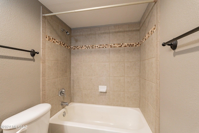 bathroom with tiled shower / bath combo and toilet