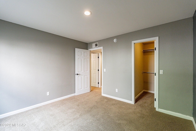 unfurnished bedroom featuring carpet flooring, a walk in closet, and a closet