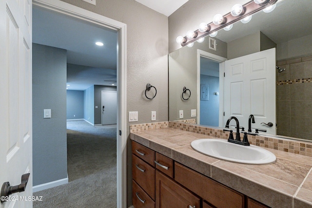 bathroom featuring tasteful backsplash, ceiling fan, vanity, and a shower