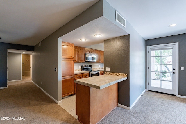 kitchen featuring kitchen peninsula, tile counters, light colored carpet, and stainless steel appliances