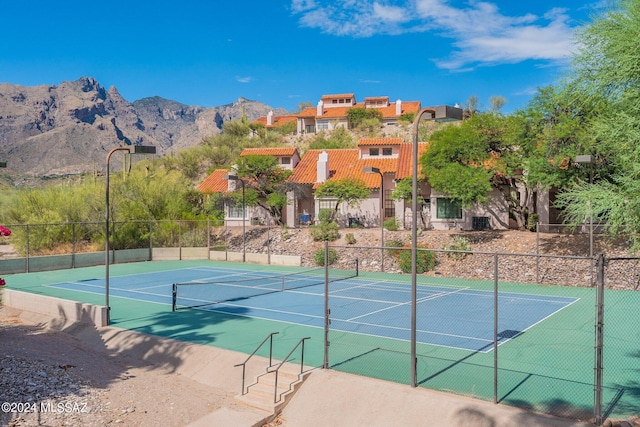 view of tennis court with basketball hoop and a mountain view