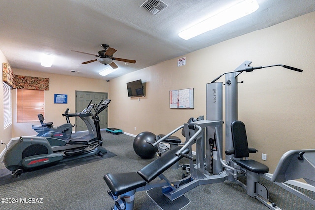 gym featuring a textured ceiling and ceiling fan