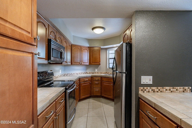 kitchen featuring appliances with stainless steel finishes, tile countertops, and light tile patterned flooring