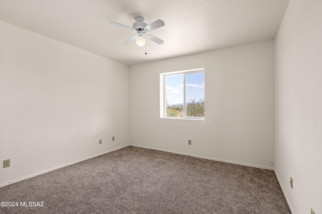 empty room featuring ceiling fan, baseboards, and carpet
