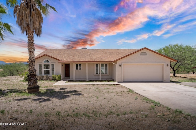 ranch-style home with a garage, driveway, and stucco siding