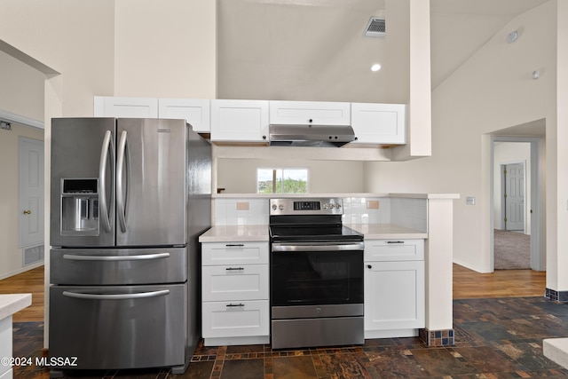 kitchen with stainless steel appliances, white cabinets, tasteful backsplash, and high vaulted ceiling