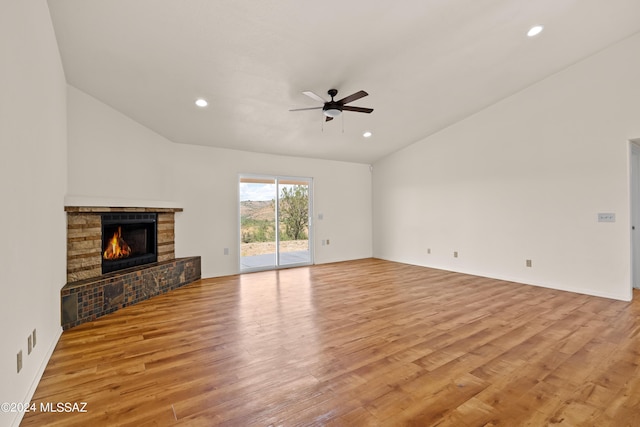 unfurnished living room with a lit fireplace, light wood-type flooring, ceiling fan, and vaulted ceiling