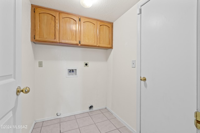 laundry area with a textured ceiling, cabinets, electric dryer hookup, hookup for a washing machine, and light tile patterned flooring