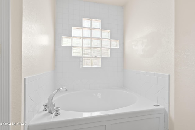 bathroom featuring a textured wall and a garden tub