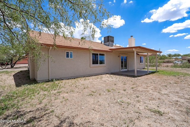 back of property featuring a patio area, central air condition unit, stucco siding, and a chimney