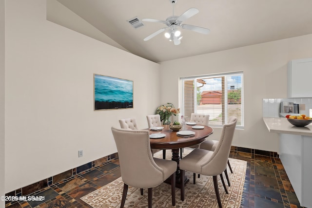 dining area with visible vents, baseboards, ceiling fan, vaulted ceiling, and stone tile floors