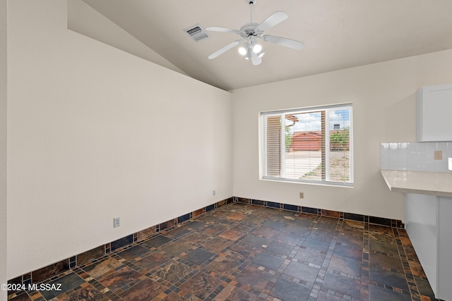 spare room featuring baseboards, a ceiling fan, visible vents, lofted ceiling, and stone finish flooring