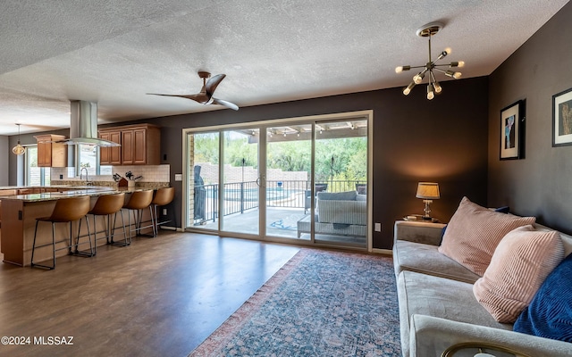 living room featuring sink and ceiling fan with notable chandelier