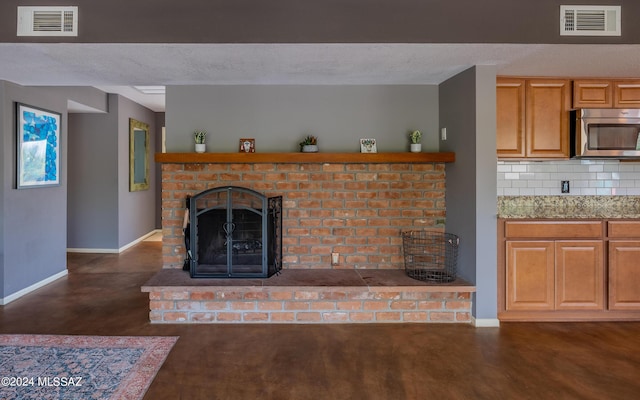 living room featuring a brick fireplace and a textured ceiling