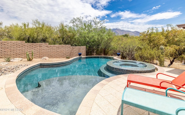 view of pool featuring a patio area, a mountain view, and an in ground hot tub