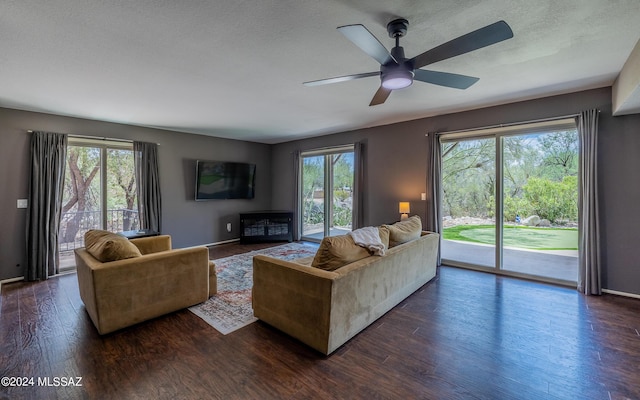 living room with ceiling fan, dark wood-type flooring, and a textured ceiling