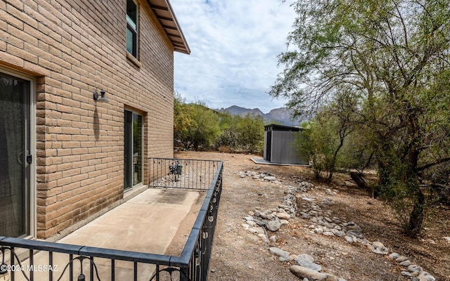 view of side of home with a storage shed and a mountain view