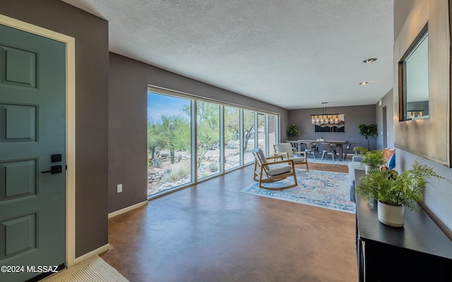 living room featuring a textured ceiling, an inviting chandelier, and concrete floors