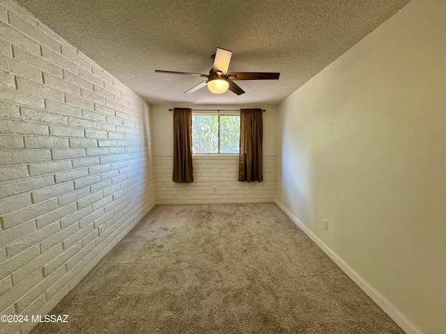 unfurnished room featuring ceiling fan, light colored carpet, a textured ceiling, and brick wall