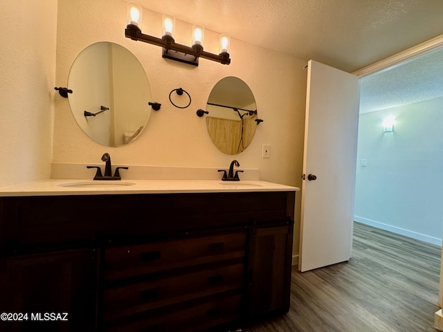 bathroom with wood-type flooring, vanity, and a textured ceiling