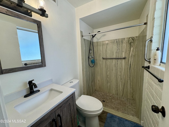 bathroom with tiled shower, vanity, wood-type flooring, and toilet