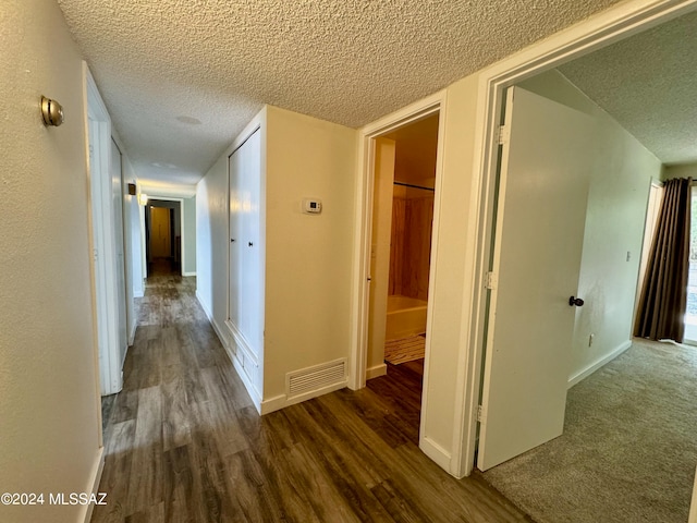 corridor with dark hardwood / wood-style flooring and a textured ceiling