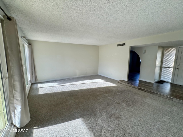 unfurnished room with a textured ceiling and dark hardwood / wood-style flooring