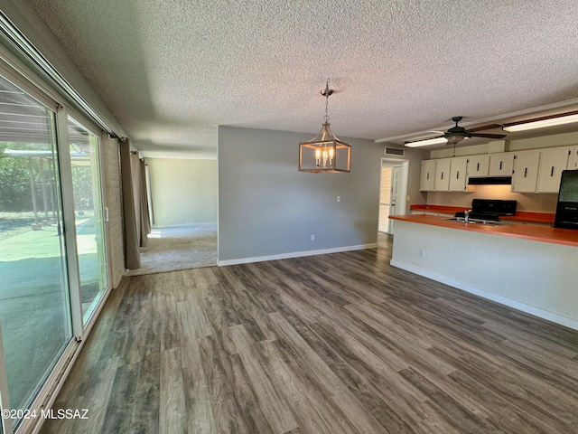 kitchen with sink, dark wood-type flooring, hanging light fixtures, a textured ceiling, and white cabinets