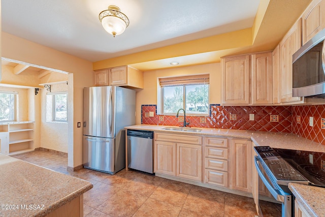 kitchen with light brown cabinets, stainless steel appliances, a sink, light countertops, and a wealth of natural light