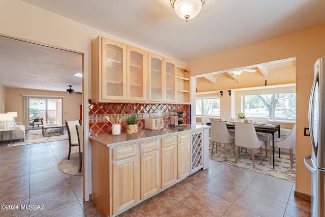 kitchen featuring light brown cabinets, glass insert cabinets, a ceiling fan, and freestanding refrigerator