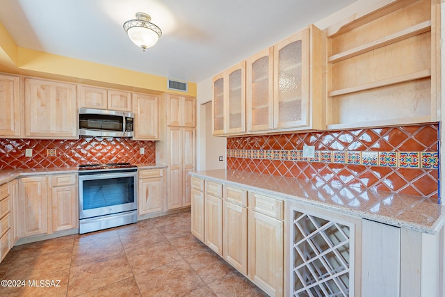 kitchen featuring light brown cabinets, visible vents, stainless steel appliances, and light stone counters