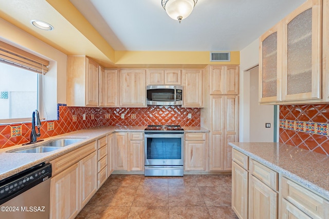 kitchen featuring stainless steel appliances, visible vents, light brown cabinetry, glass insert cabinets, and a sink