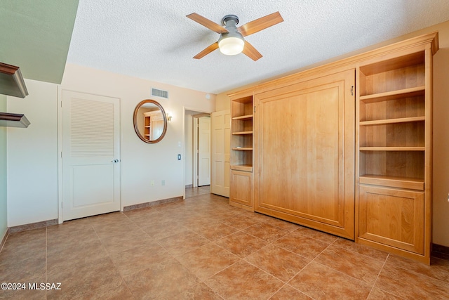 unfurnished bedroom with a textured ceiling, a ceiling fan, visible vents, and baseboards