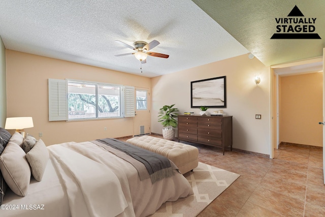 bedroom featuring a ceiling fan, a textured ceiling, baseboards, and light tile patterned floors