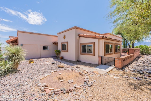 view of front of home with a tiled roof, fence, and stucco siding